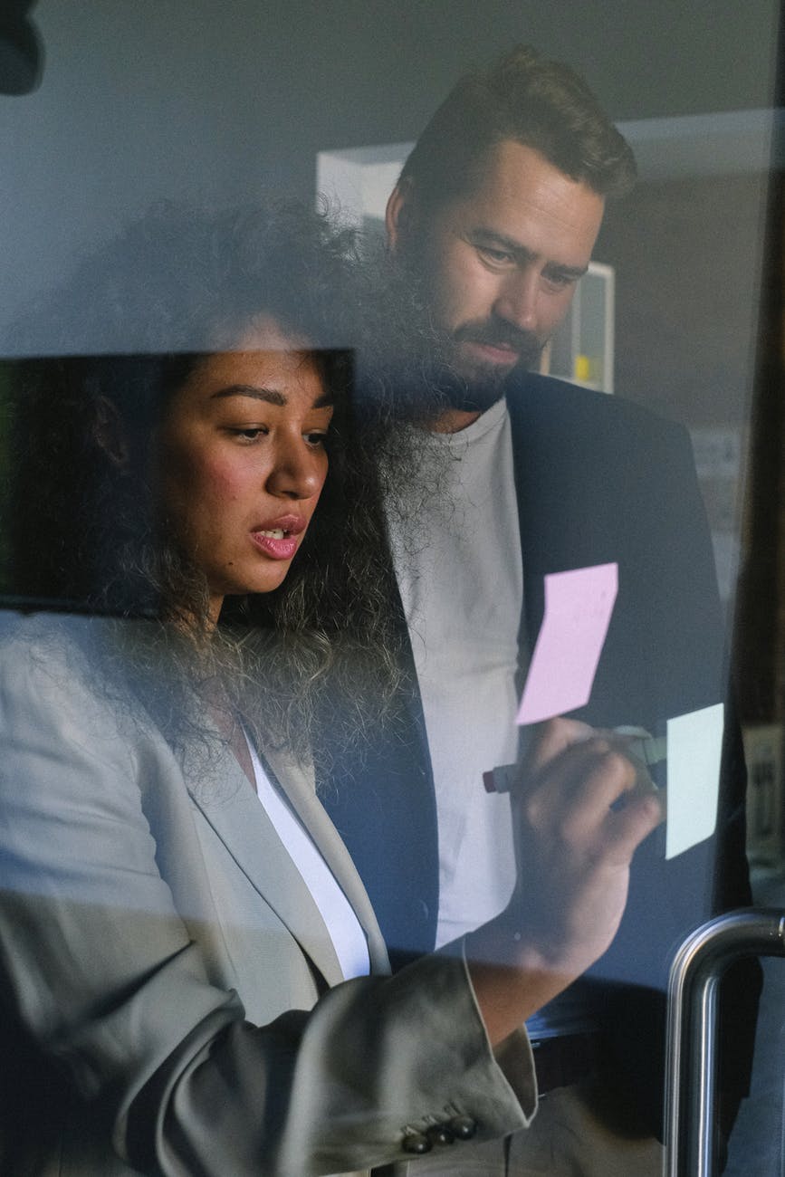 focused multiethnic business partners communicating and writing on stickers